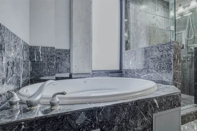 a bathroom with a granite countertop bathtub and shower