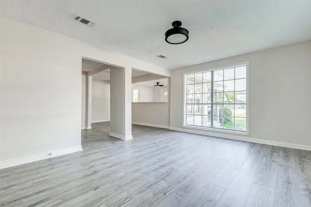 an empty room with wooden floor and windows