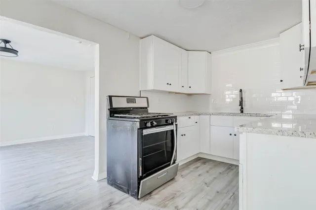 a kitchen with granite countertop white cabinets and stainless steel appliances