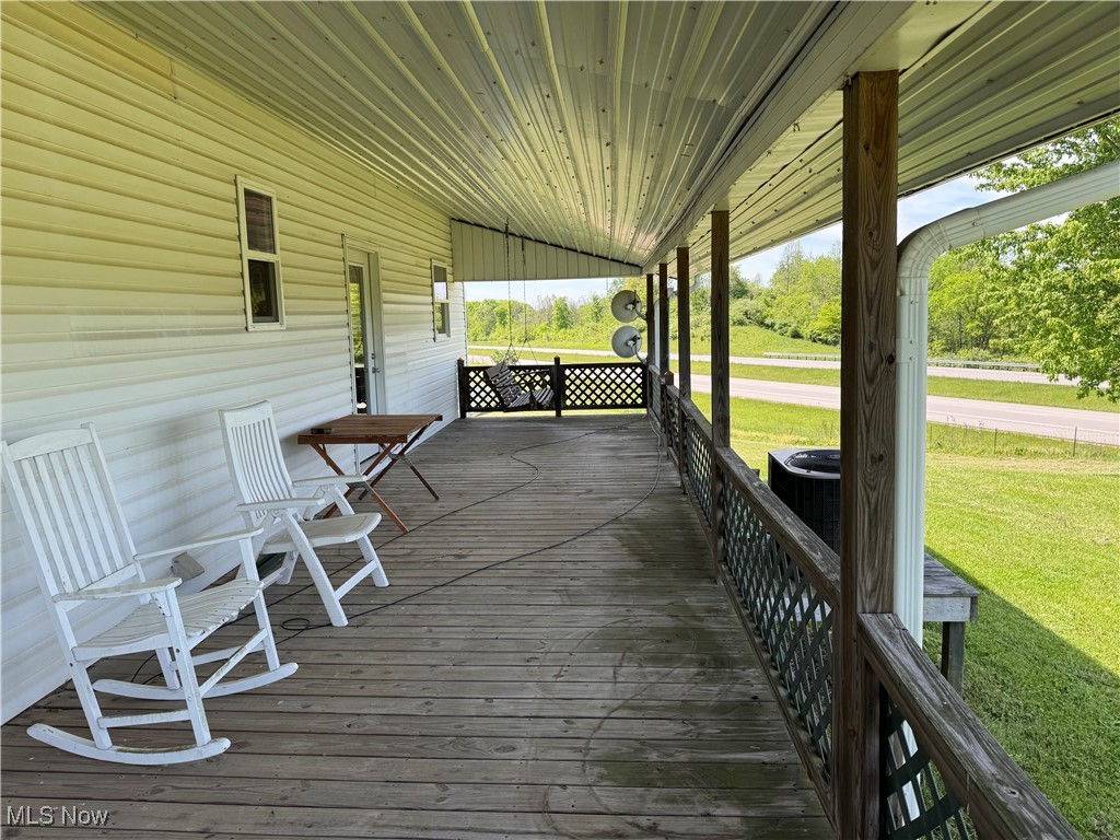 6255 Highland Ridge Road Lowell, OH 45744 - Photo 21 of 40 Deck with covered porch, central air condition unit, and a lawn