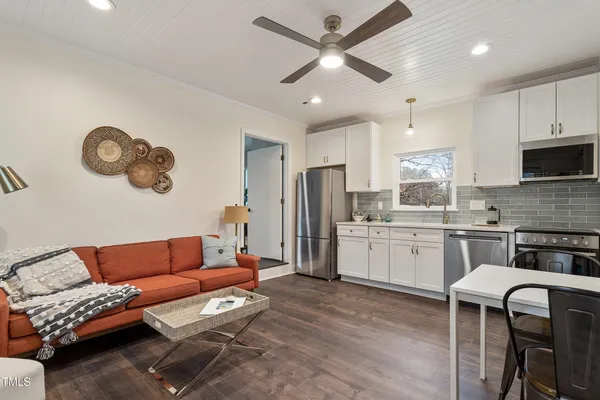 a living room with stainless steel appliances kitchen island granite countertop furniture and a wooden floor
