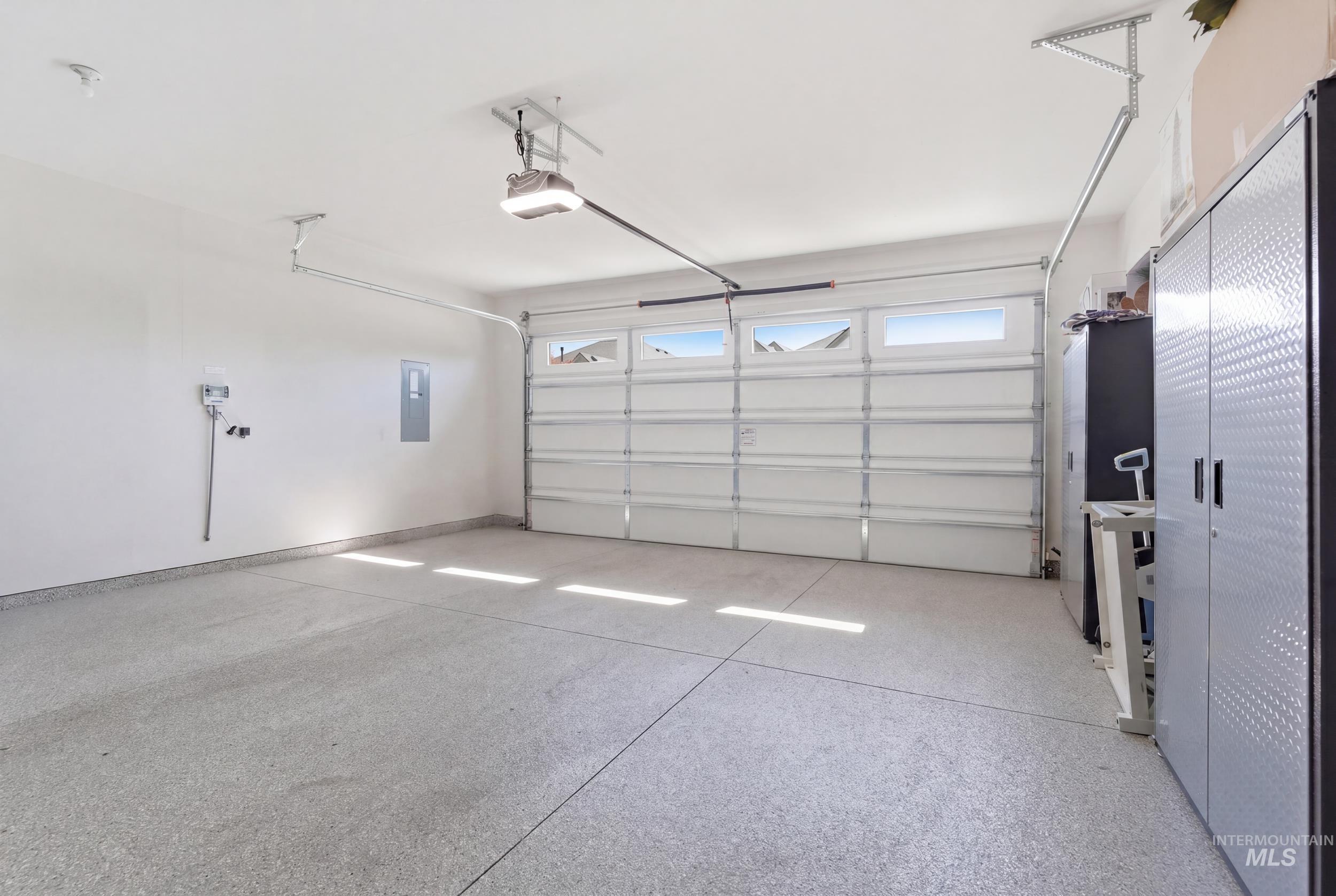 6347 South Utmost Lane Meridian, ID 83642 - Photo 31 of 37 Spacious garage featuring a durable epoxy-coated concrete floor, white painted walls, and an automatic garage door with upper window panels