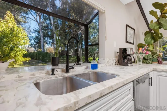 a kitchen sink with granite countertop a sink and a large mirror next to a window