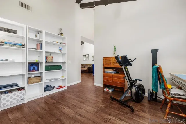 a room with gym equipment and wooden floor