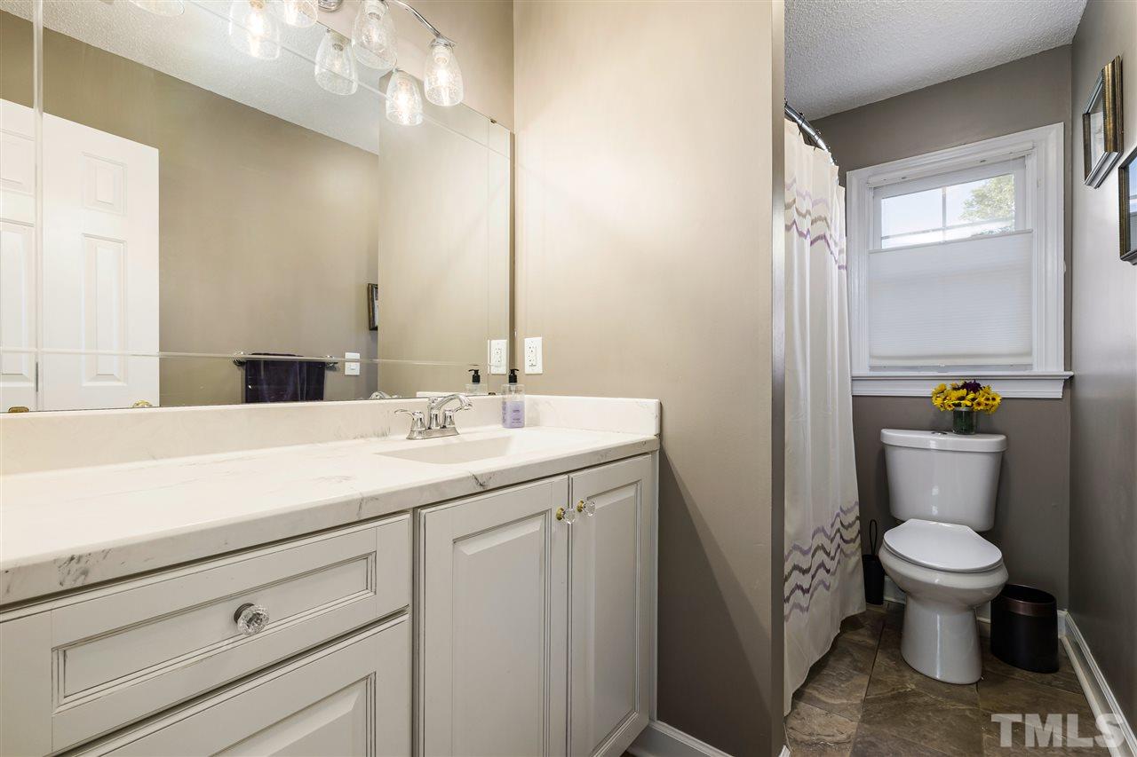 5633 Raddington Street Raleigh, NC 27613 - Photo 19 of 25 a bathroom with a granite countertop toilet sink and mirror