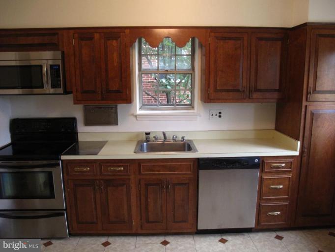 9508 Wire Avenue Silver Spring, MD 20901 - Photo 9 of 10 a kitchen with stainless steel appliances granite countertop wooden cabinets and a stove top oven