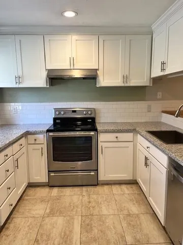 a kitchen with granite countertop a stove top oven microwave and cabinets
