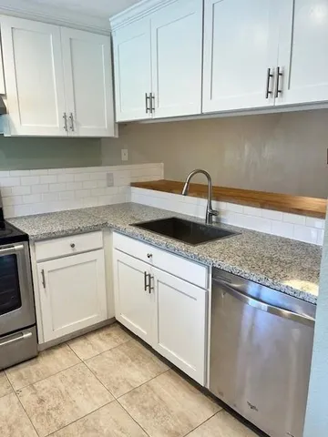 a kitchen with granite countertop white cabinets and a sink