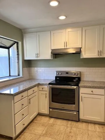 a kitchen with granite countertop white cabinets and appliances