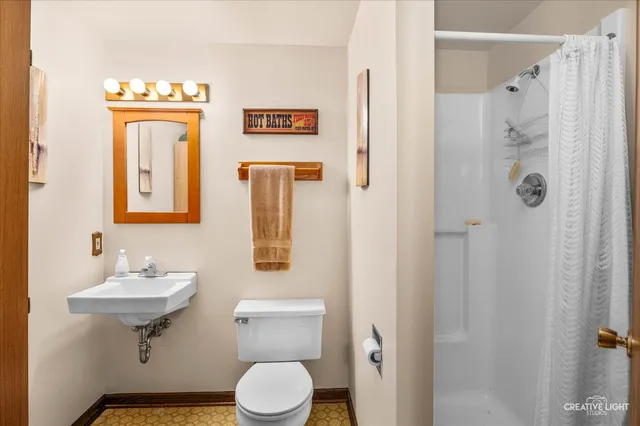 a bathroom with a toilet a sink shower and mirror