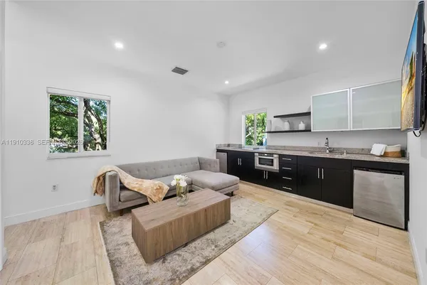 a living room with stainless steel appliances granite countertop furniture and a wooden floor