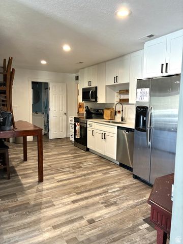 175 Eagle Street Eureka, UT 84628 - Photo 4 of 31 Kitchen with stainless steel appliances, white cabinetry, light wood finished floors, light countertops, and recessed lighting