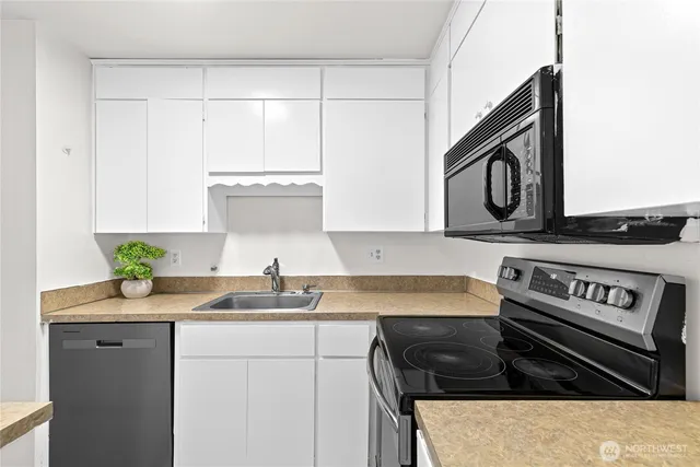 a kitchen with granite countertop a sink a stove and cabinets