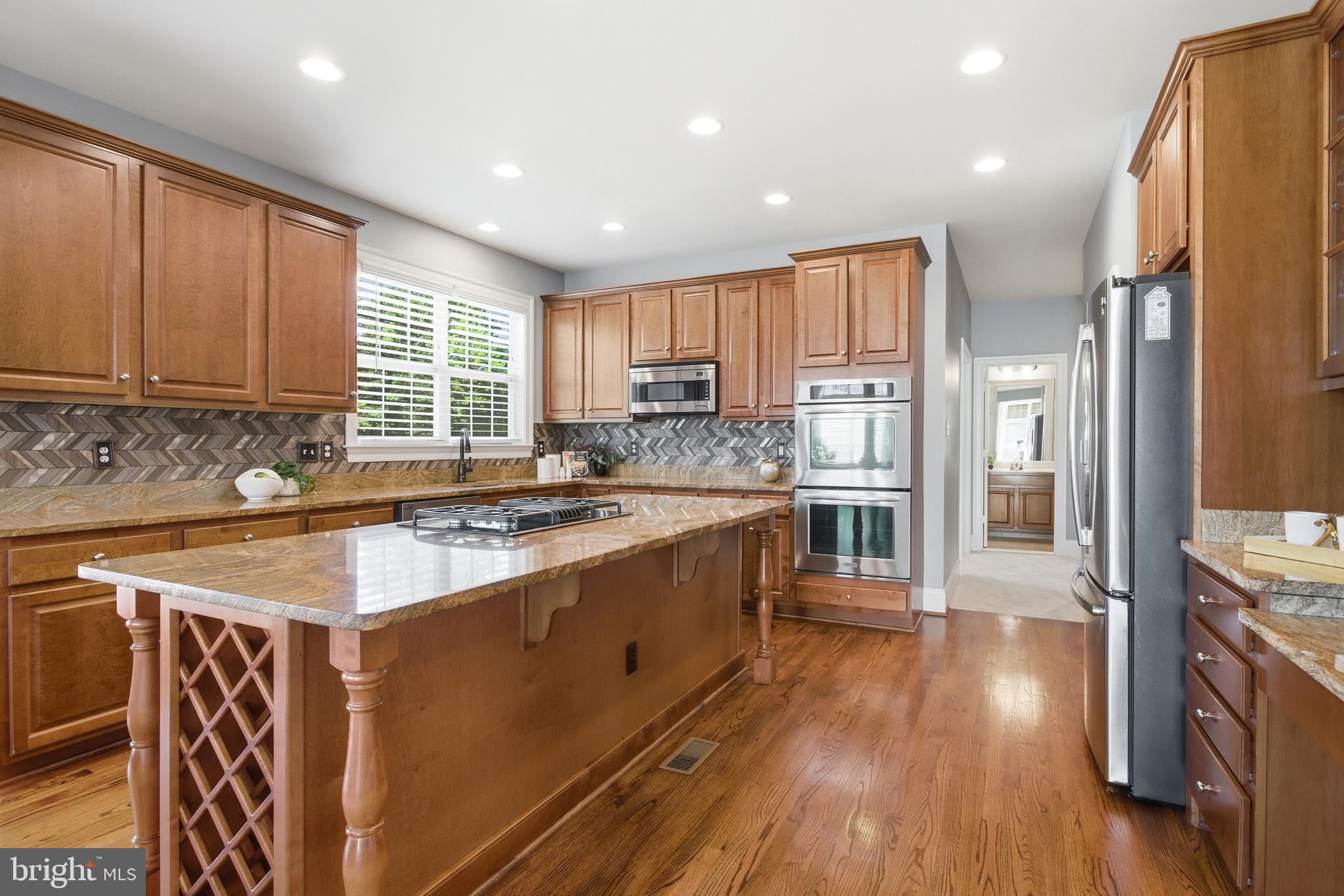 18475 Kerill Road Triangle, VA 22172 - Photo 50 of 99 a large kitchen with stainless steel appliances granite countertop a stove a sink dishwasher and a refrigerator with wooden floor