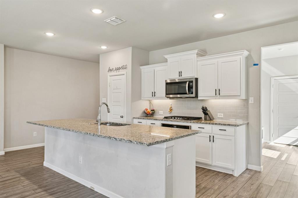 312 Scenic Point Drive Princeton, TX 75407 - Photo 13 of 40 a kitchen with granite countertop a sink a stove a microwave and wooden floor
