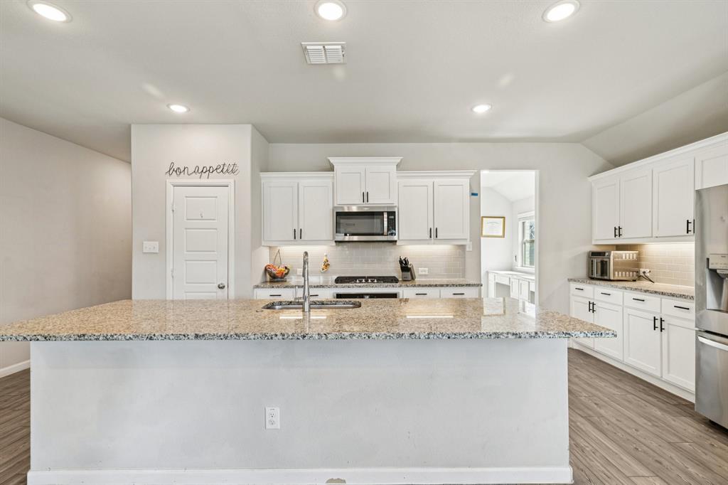 312 Scenic Point Drive Princeton, TX 75407 - Photo 3 of 40 a large kitchen with granite countertop a stove a sink a refrigerator a microwave oven with cabinets and wooden floor
