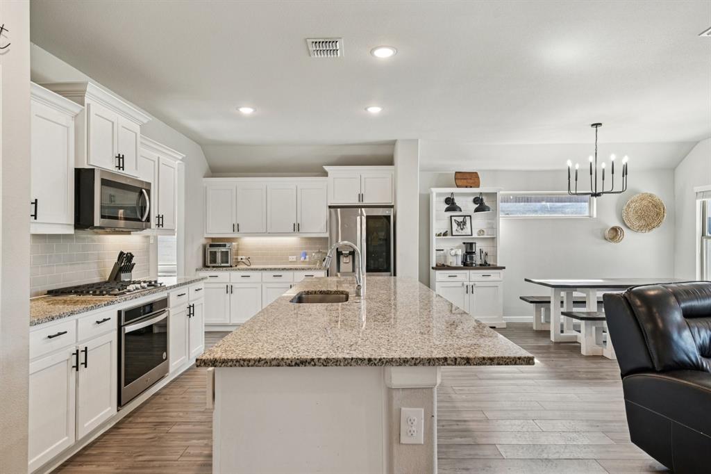 312 Scenic Point Drive Princeton, TX 75407 - Photo 4 of 40 a kitchen with granite countertop kitchen island stainless steel appliances a stove sink microwave and cabinets