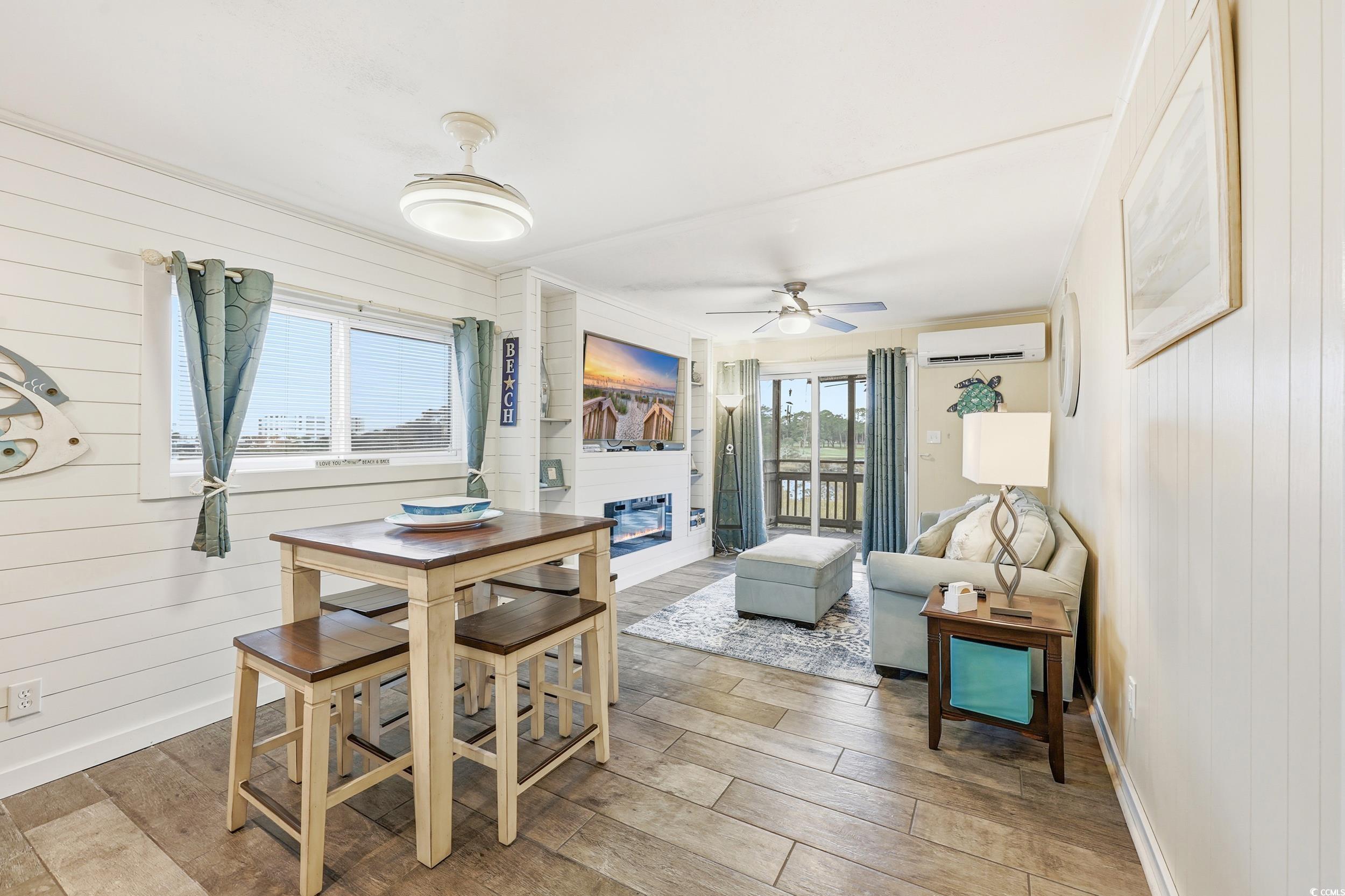 9501 Shore Drive, Unit A208 Myrtle Beach, SC 29572 - Photo 10 of 29 Dining room featuring wooden walls, wood finish floors, a fireplace, a ceiling fan, and a wall unit AC