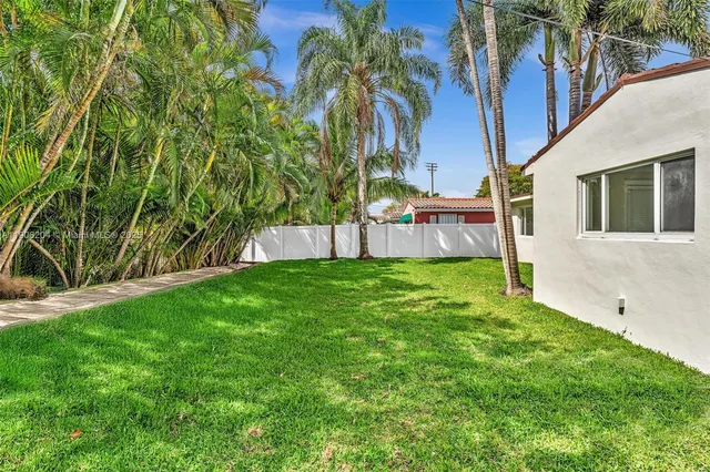 a view of house with backyard and a tree