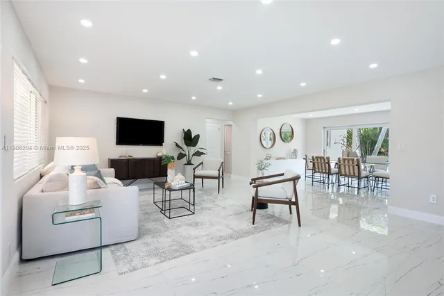 a living room with furniture a flat screen tv and a refrigerator