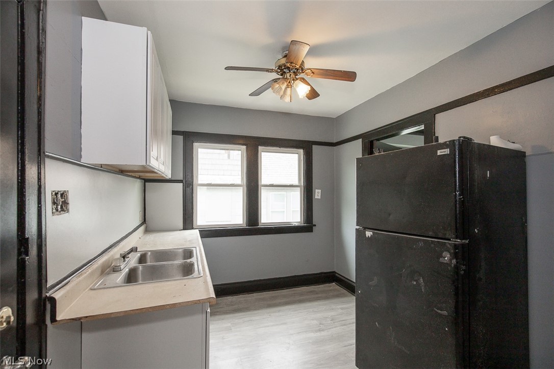 1868-1870 Lampson Road Cleveland, OH 44112 - Photo 11 of 36 Kitchen with dual windows, wood-finish flooring, a ceiling fan, and upper and lower cabinetry