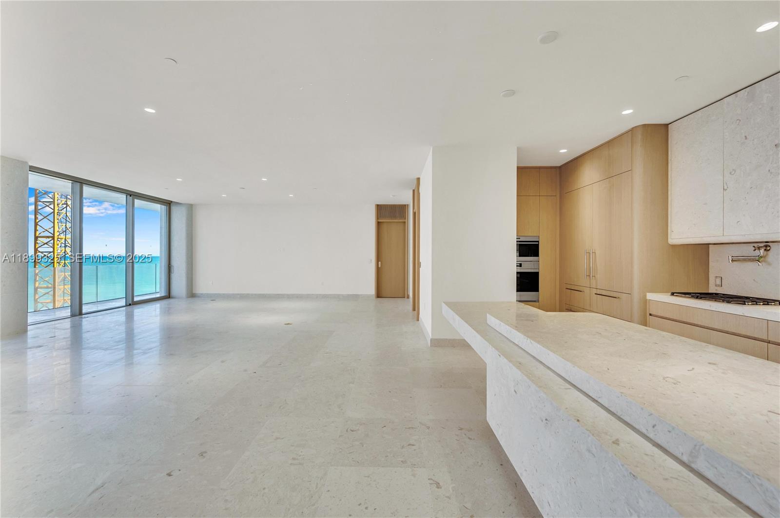 9149 Collins Avenue, Unit 602 Surfside, FL 33154 - Photo 2 of 8 a view of an empty room with wooden floor and a kitchen