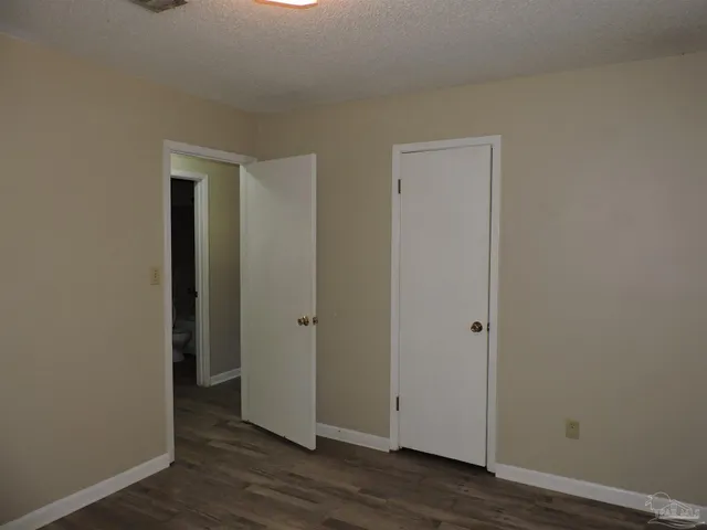 an empty room with wooden floor & closet area