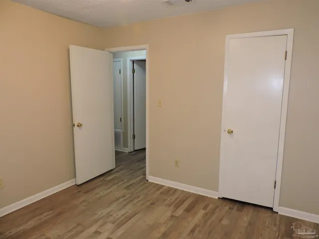 a view of an empty room with wooden floor and entrance