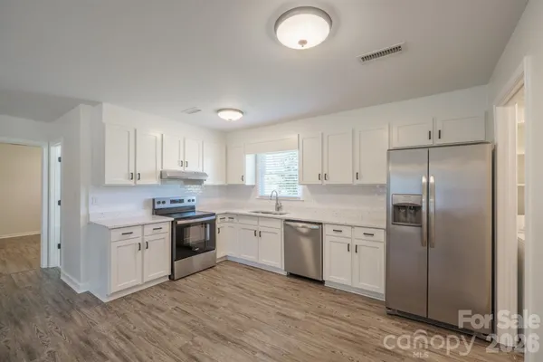 a large kitchen with cabinets stainless steel appliances and a window