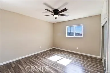 an empty room with wooden floor and ceiling fan