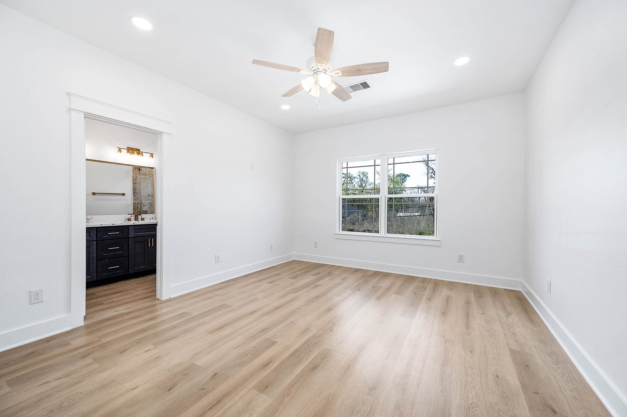 8602 Hoffman Street Houston, TX 77016 - Photo 19 of 30 Spacious primary bedroom featuring wood-style flooring, natural light, and direct access to the bathroom.