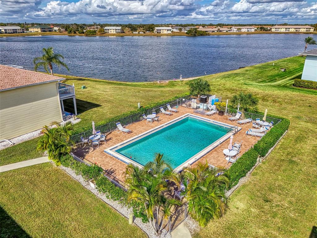 26310 Rampart Boulevard, Unit 505/E Punta Gorda, FL 33983 - Photo 45 of 64 a view of a backyard with lawn chairs under an umbrella