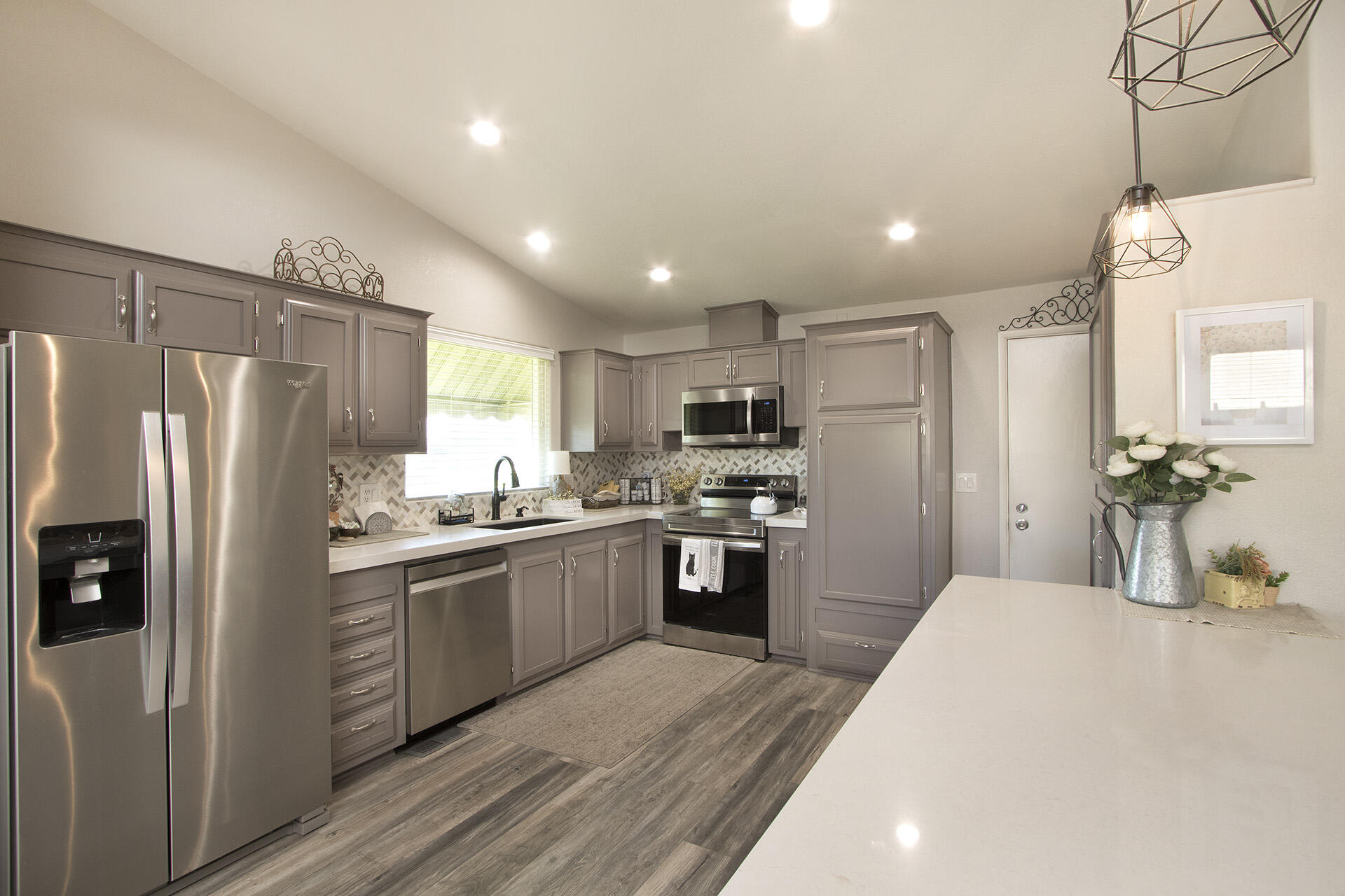74986 Conestoga Thousand Palms, CA 92276 - Photo 4 of 29 a kitchen with stainless steel appliances granite countertop a refrigerator a sink dishwasher a stove and white cabinets with wooden floor