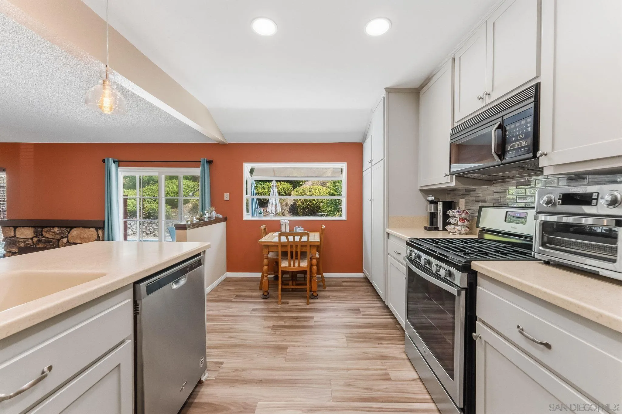 10565 Strathmore Drive Santee, CA 92071 - Photo 20 of 59 a kitchen with stainless steel appliances granite countertop a stove top oven a sink dishwasher a dining table and chairs with wooden floor