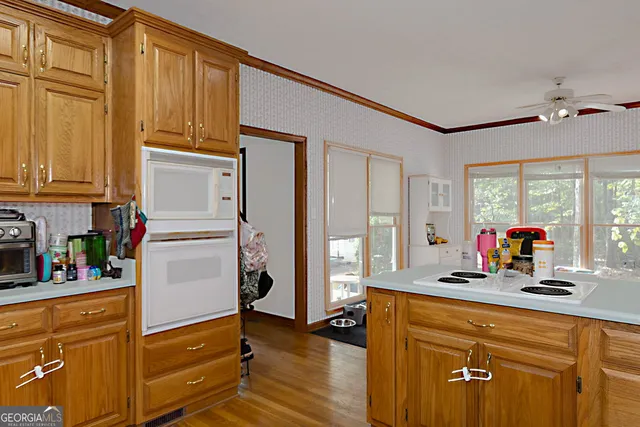 a view of a kitchen with kitchen island a large window cabinets a sink and stainless steel appliances