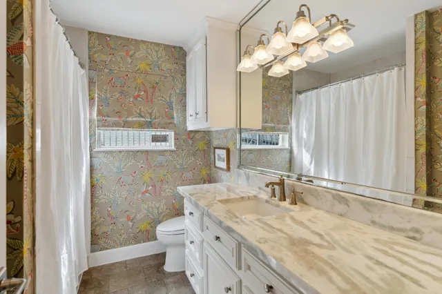 a view of a brick house with a large windows and a yard with plants and large trees