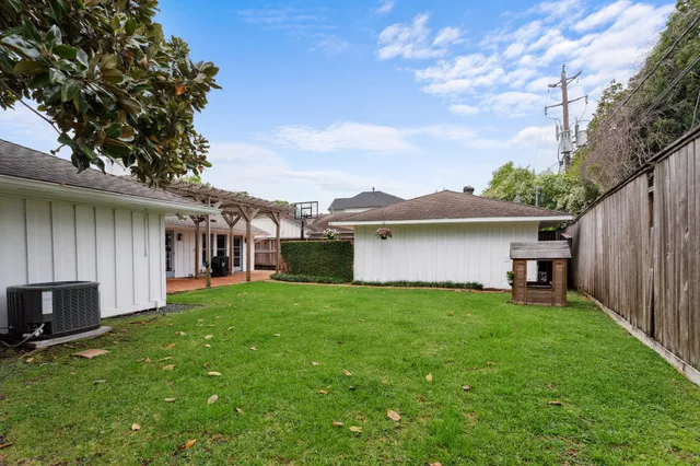 a view of a house with a yard plants and large tree