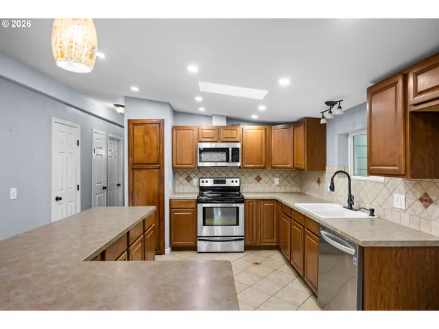 a kitchen with stainless steel appliances granite countertop a sink a stove and a refrigerator