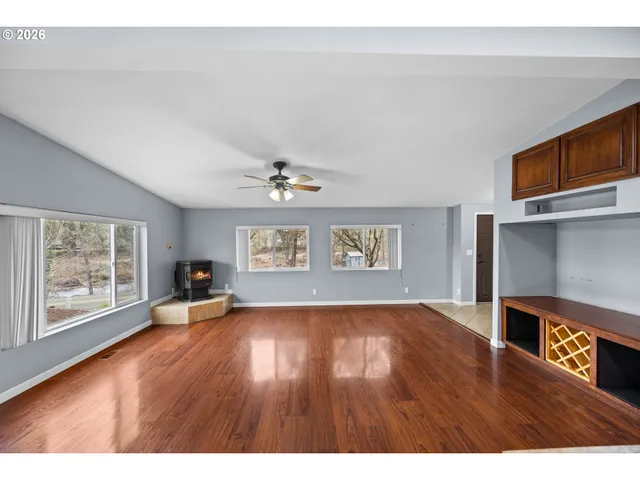 a view of an empty room with a window and wooden floor