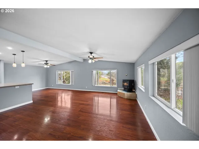 a view of an empty room with window and wooden floor
