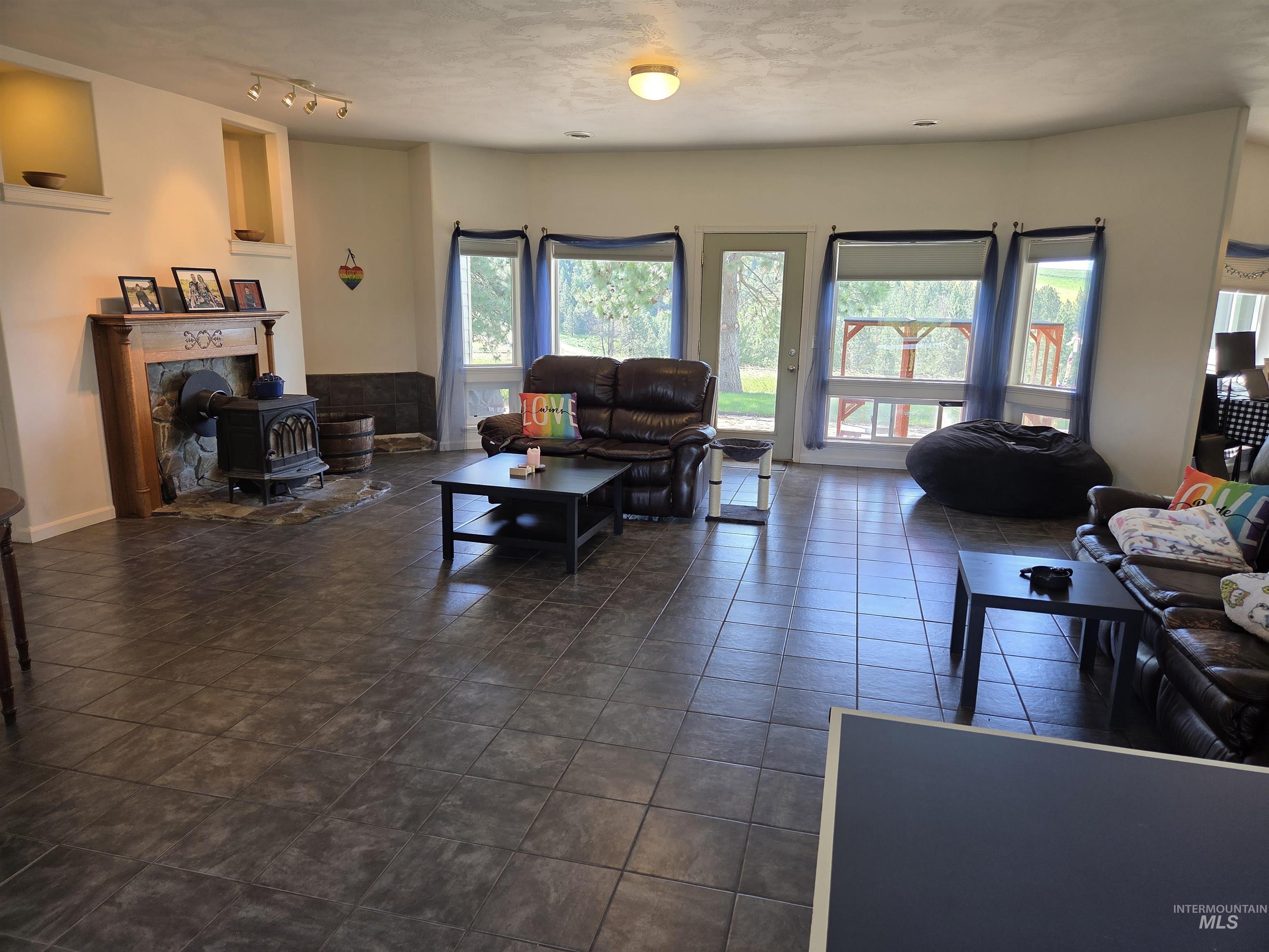 1085 Wallen Road Moscow, ID 83843 - Photo 15 of 50 Spacious living area featuring large format floor tiles, a prominent wood-burning stove with a stone hearth, and a wood mantel