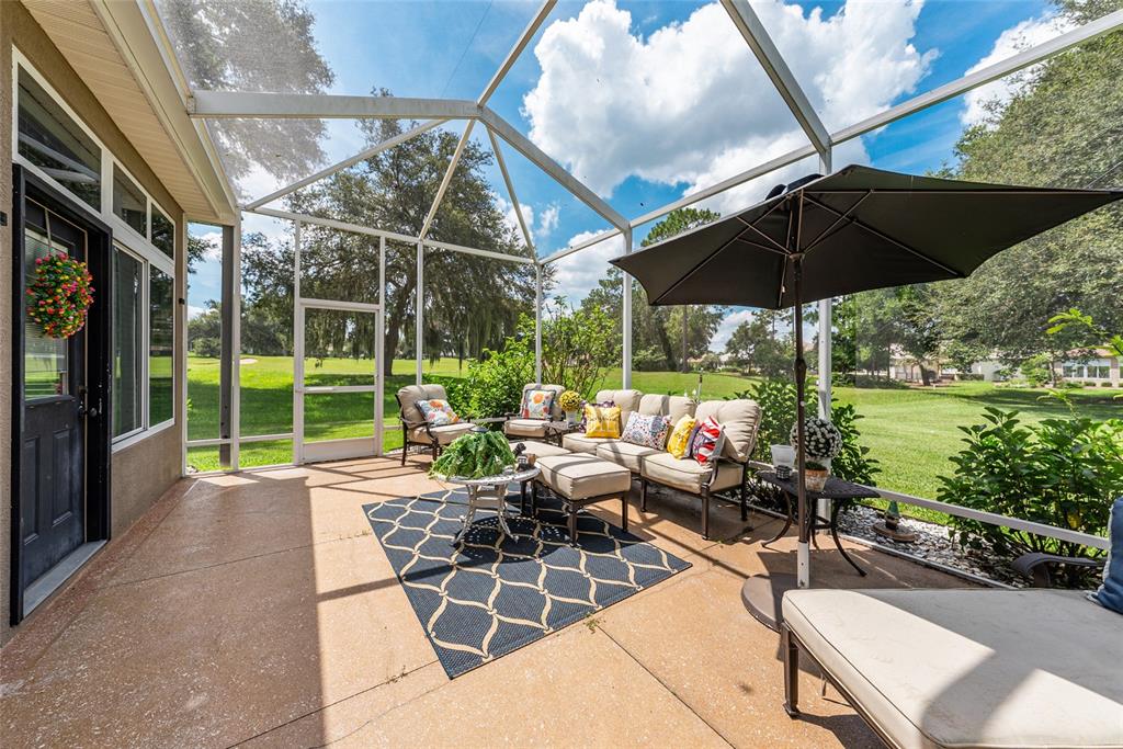 12895 Southeast 91st Terrace Road Summerfield, FL 34491 - Photo 66 of 99 a view of a patio with table and chairs under an umbrella with a garden