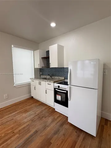 a kitchen with granite countertop a refrigerator and a stove top oven