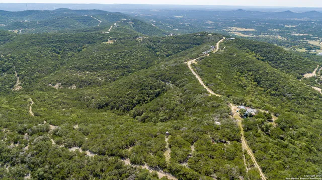an aerial view of residential houses with outdoor space and trees
