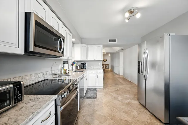 a kitchen with a sink a microwave a refrigerator and cabinets