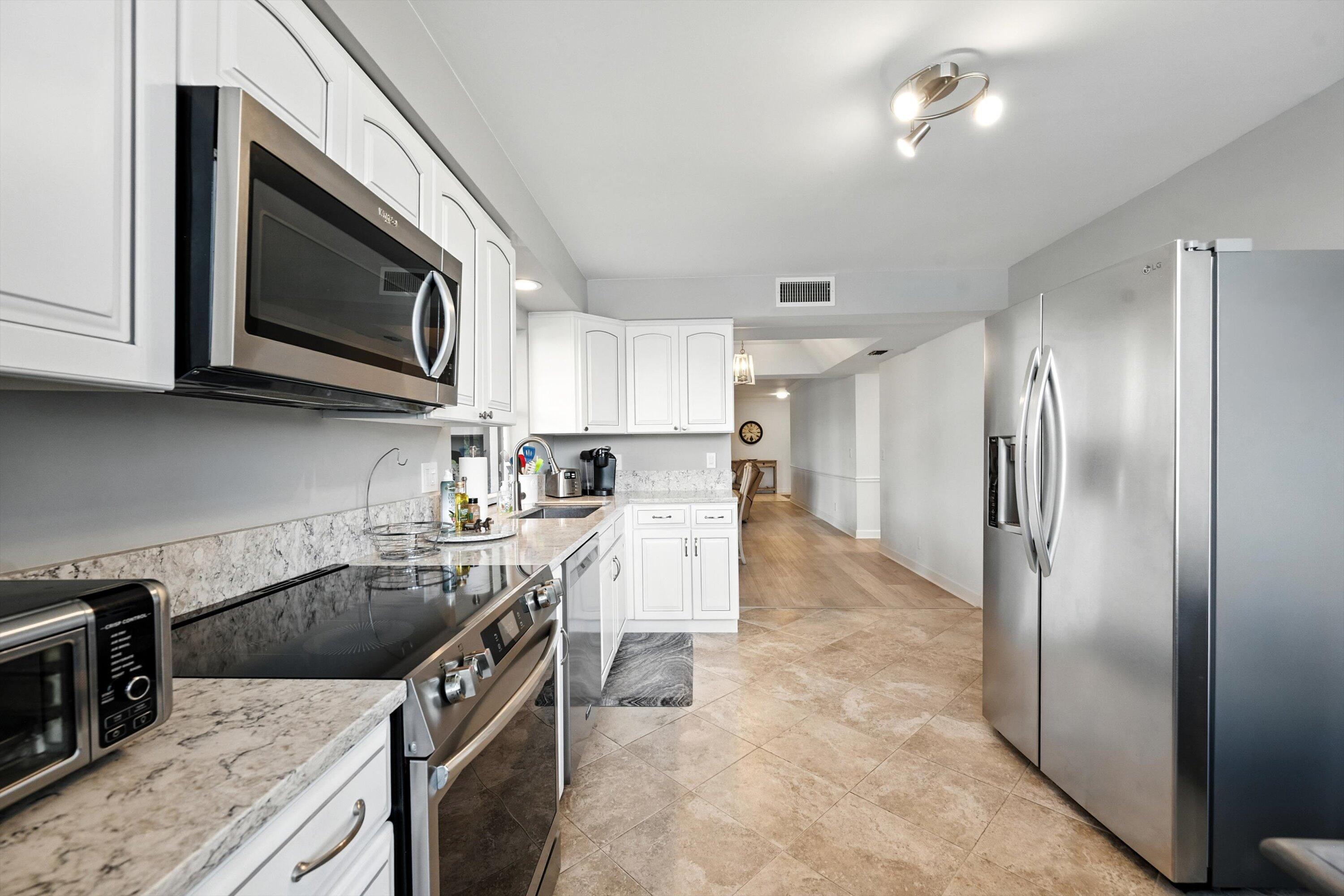 16913 Waterbend Drive, Unit 165 Jupiter, FL 33477 - Photo 14 of 39 a kitchen with a sink a microwave a refrigerator and cabinets