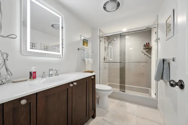 a bathroom with a double vanity sink toilet mirror and shower