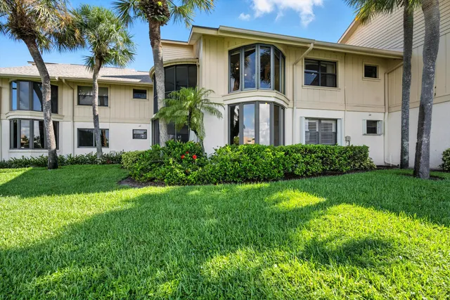 a view of a white house with a big yard and potted plants