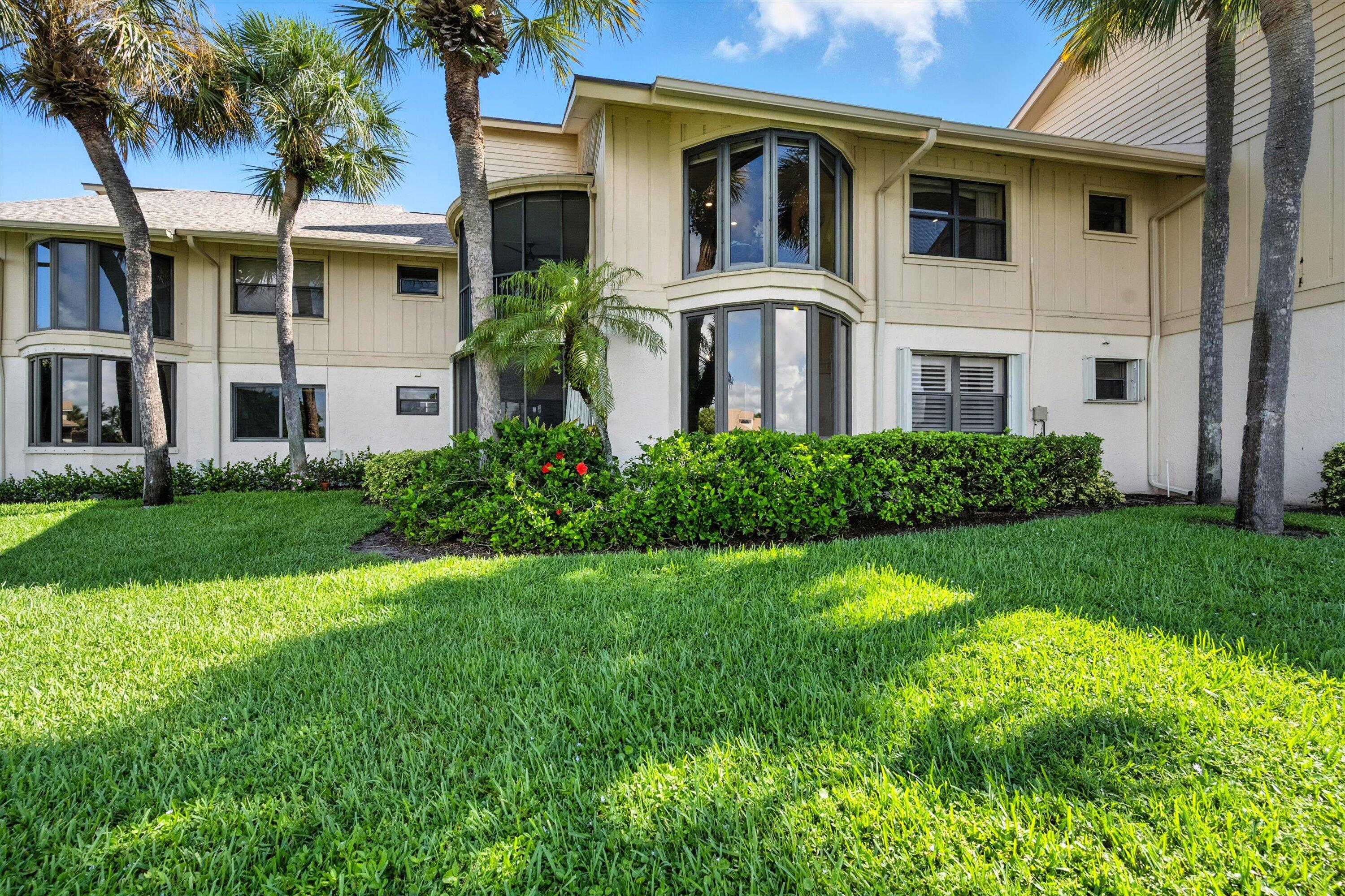 16913 Waterbend Drive, Unit 165 Jupiter, FL 33477 - Photo 28 of 39 a view of a white house with a big yard and potted plants