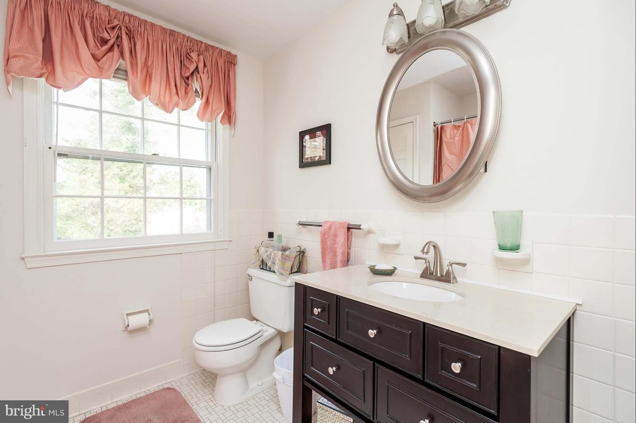 5918 Charlesmead Road Baltimore, MD 21212 - Photo 19 of 27 a bathroom with a toilet a sink a mirror a vanity and a window